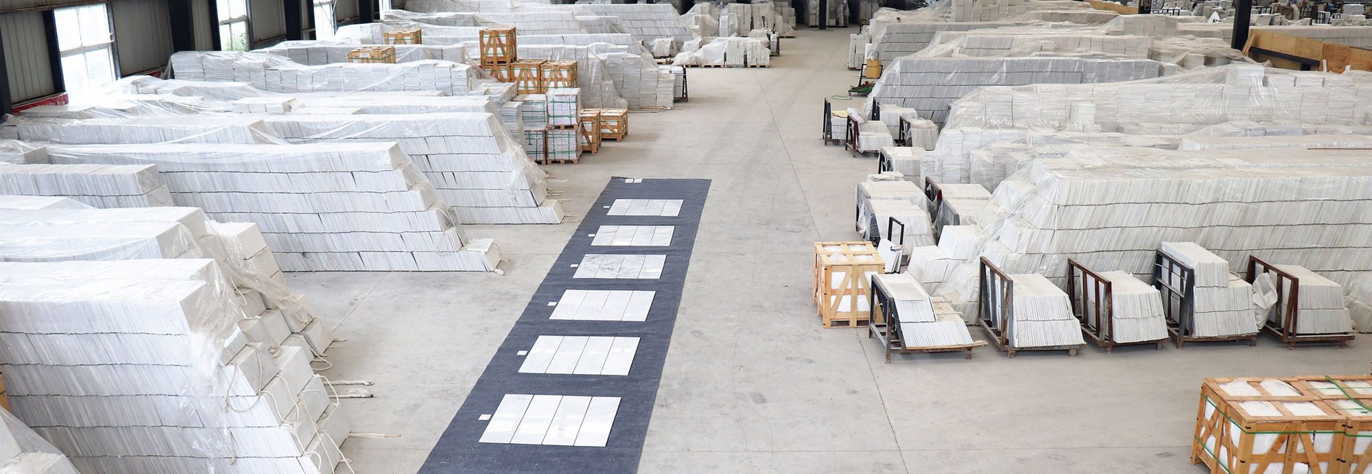 A wide view of the warehouse: tiles laid out on the floor and crates stacked behind