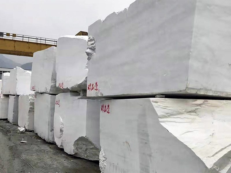White marble blocks stacked in the yard with red 环石通 marks painted on their faces