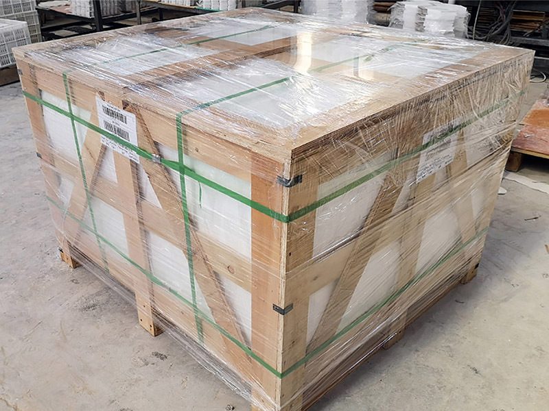 A strapped wooden export crate with a green label in the packing area