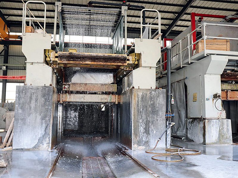 A gang saw frame in the plant with a marble block loaded beneath the blades