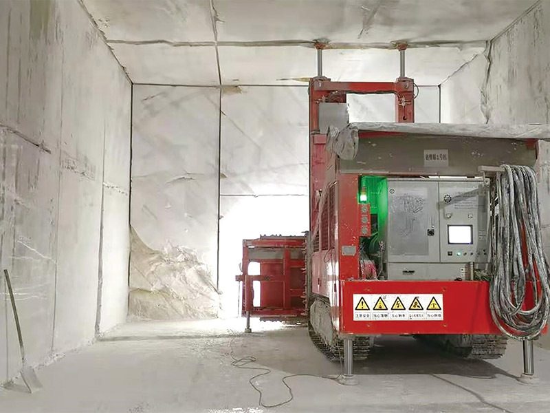 A red chain saw machine cutting a bench inside an underground marble chamber