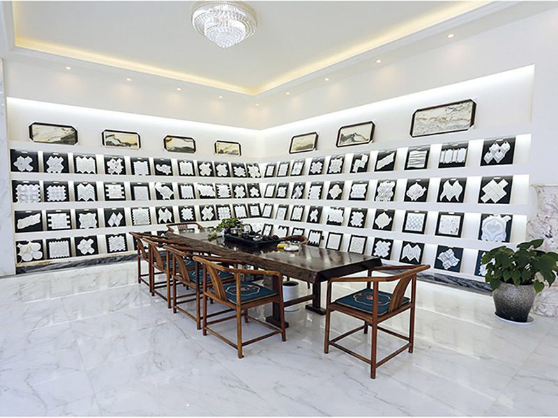 A wall of framed mosaic samples above a marble tea table