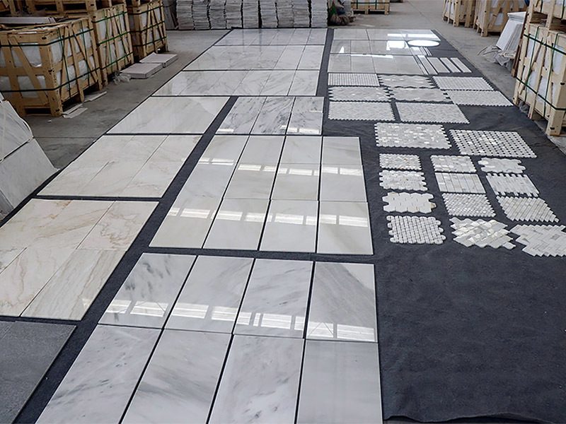 Mosaic and tile sheets laid out on the warehouse floor
