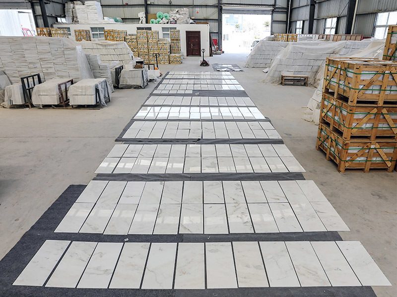 Tiles laid out in a grid on the warehouse floor for inspection