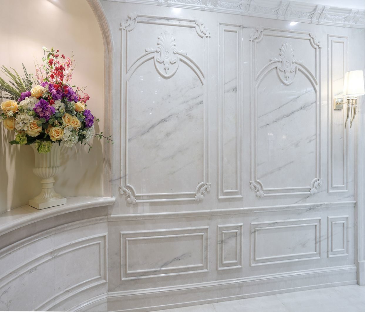 A carved white marble wall panel with a floral relief, framed by mouldings
